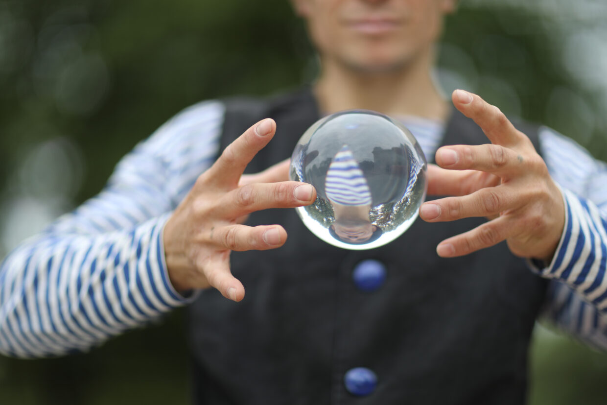Transparent magic ball with reflection in the hands of a clown